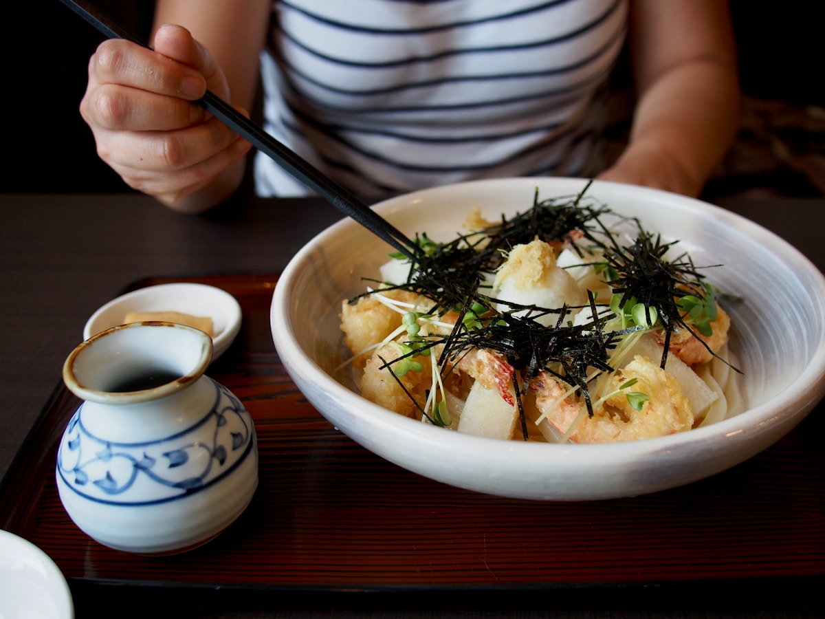 Người phụ nữ thưởng thức món Nhật với đũa và nước dùng dashi