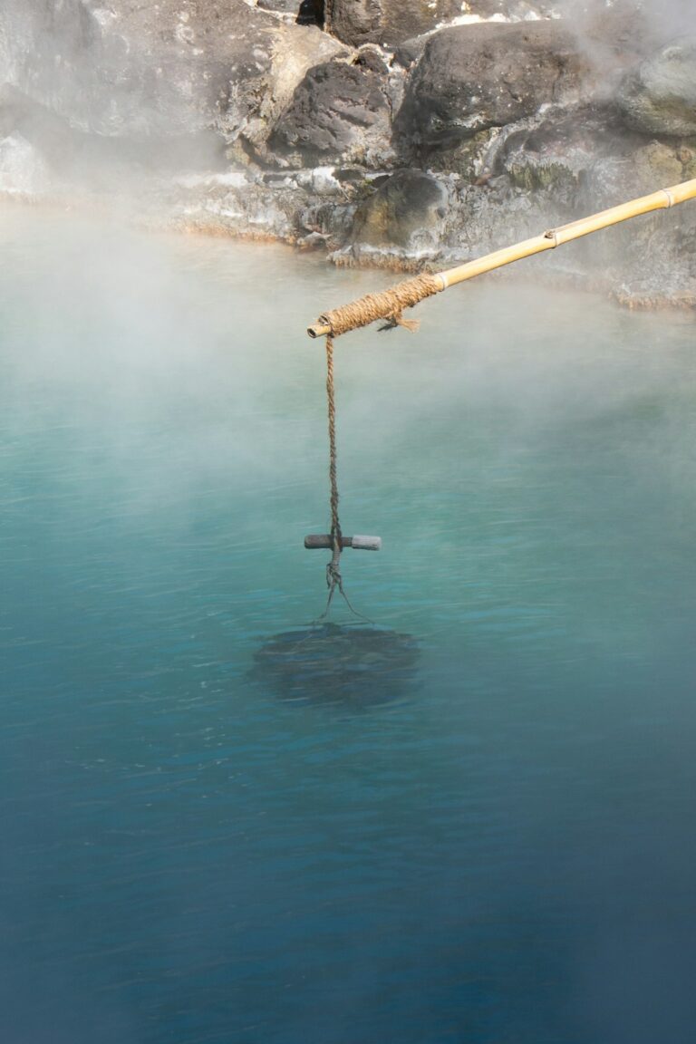 Steamy blue onsen water with traditional wooden ladle and rocks