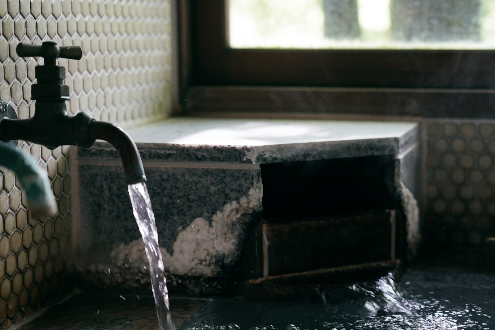 Vòi nước onsen truyền thống Nhật Bản bên cửa sổ nhìn ra vườn